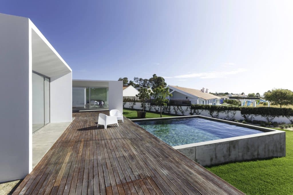 Raised pool wall beside a wood deck and lawn, showing how decking adds to a pool budget in Hammond